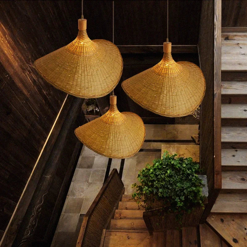 Wren handcrafted woven bamboo pendant light hanging above a wooden dining table in a warm interior