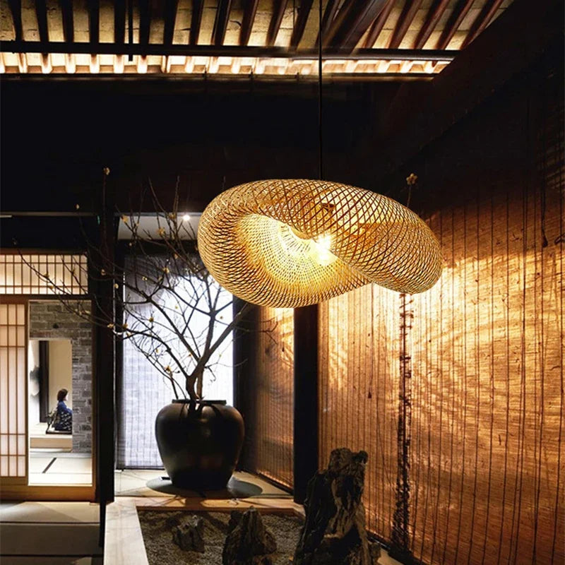 Wren handcrafted woven bamboo pendant light hanging above a wooden dining table in a warm interior