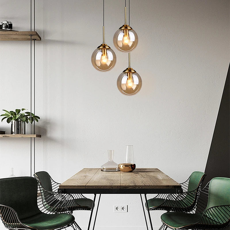 Orla amber glass and metal pendant light hanging above a bedside table in a Nordic-style bedroom