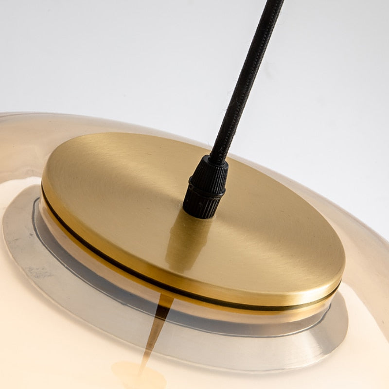 Amba clear jelly globe pendant light with gold fitting hanging above a dining table