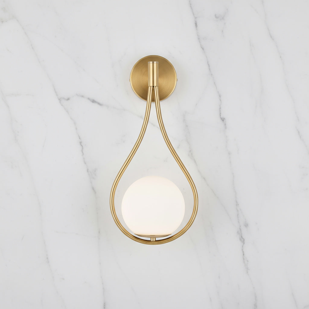 Livi gold Nordic wall sconce mounted beside a bed in a minimalist bedroom