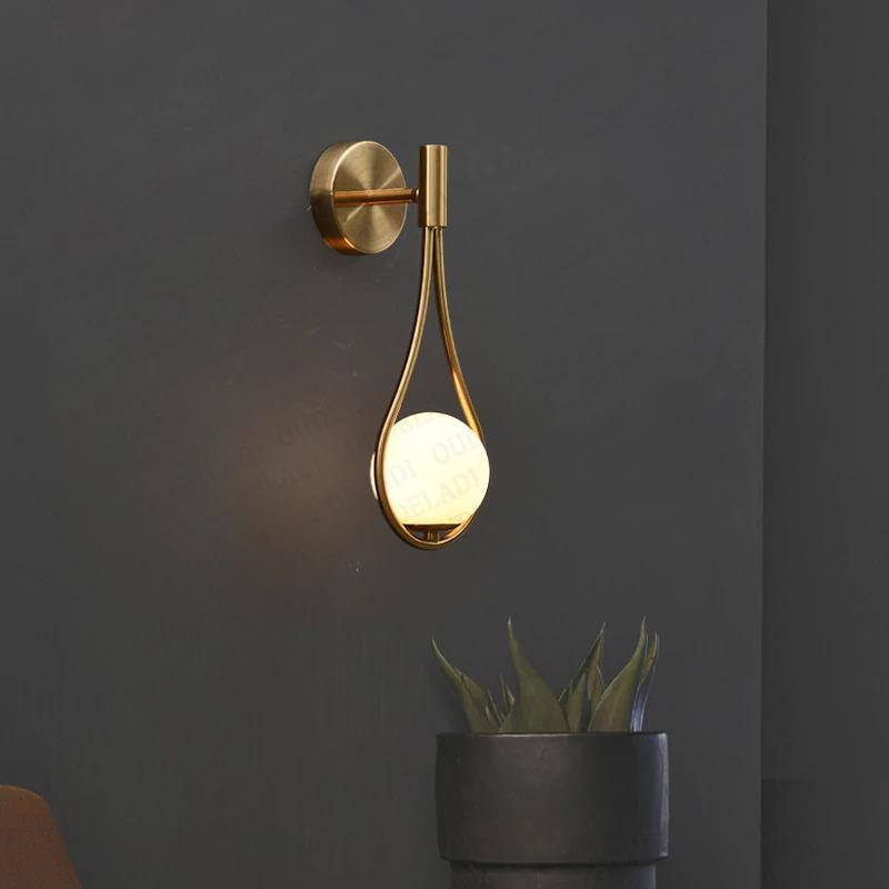 Livi gold Nordic wall sconce mounted beside a bed in a minimalist bedroom